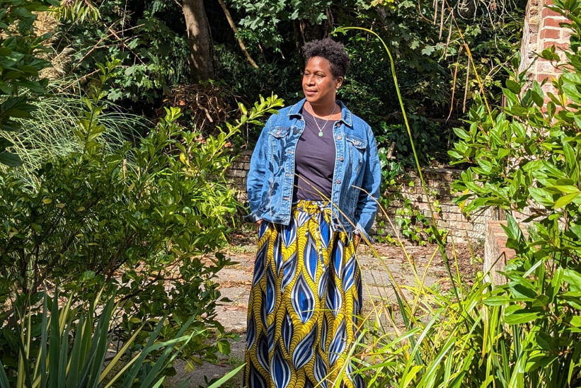 black woman staning amongst tree with sun light falling on her face profile
