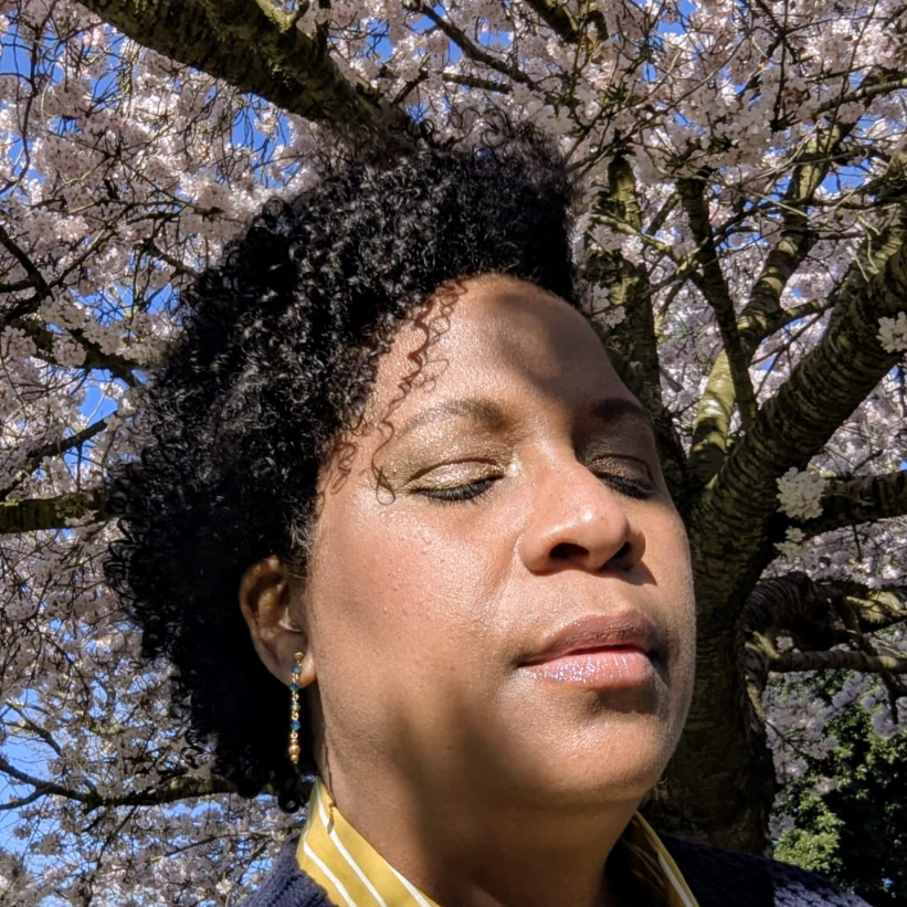 black lady with curly hair under cherry blossom tree