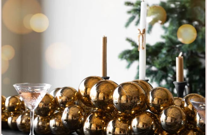 Rockett St George antique gold garland on a dining table with candles and a Christmas tree in the backdrop
