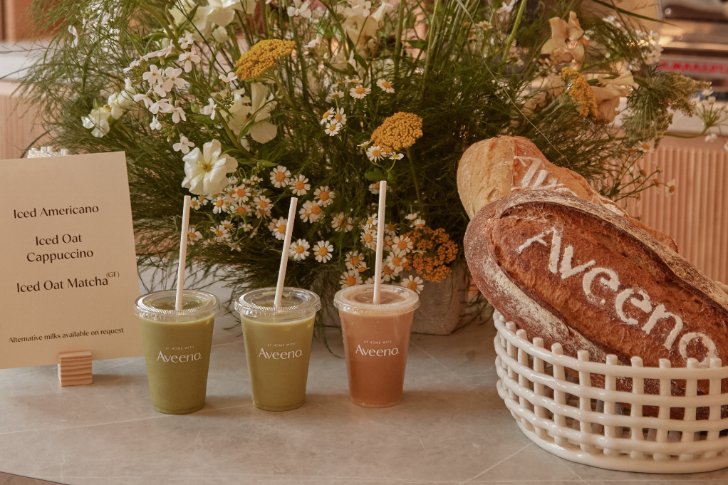 table with iced coffee and matcha with loaves of rustic bread, flower in the background