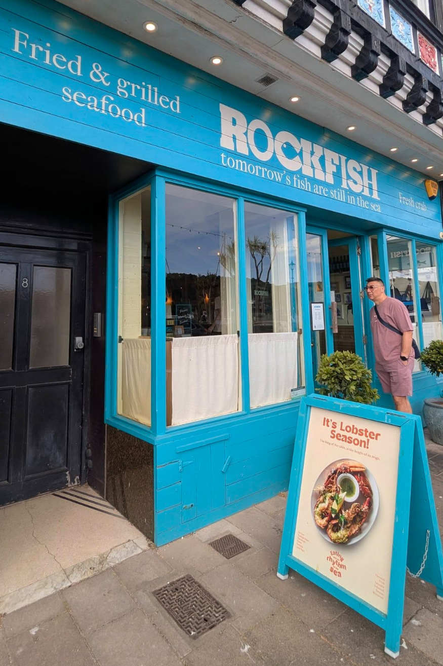 man standing in front of Rockfish restaurant