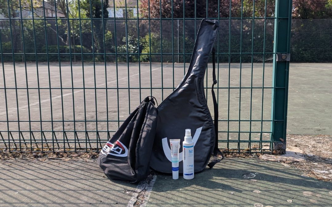 Ultrasun Sport Spray and Photo Age on tennis court leaning against tennis racket case